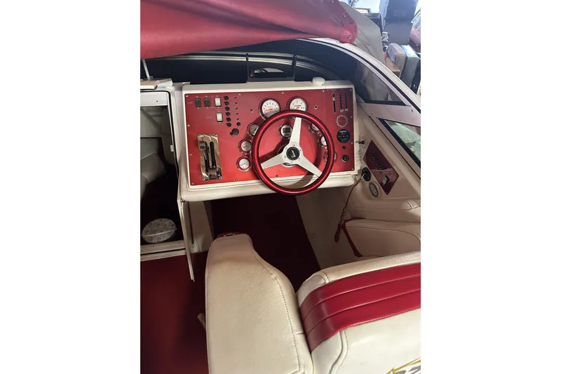 Slide: The Image of 2005 Fountain 27 Fever boat cockpit with red and white interior, featuring gauges and steering wheel. - 9