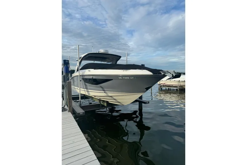 Slide: The Image of 2023 Sea Ray SLX 350 boat docked on calm water under a cloudy sky. - 2