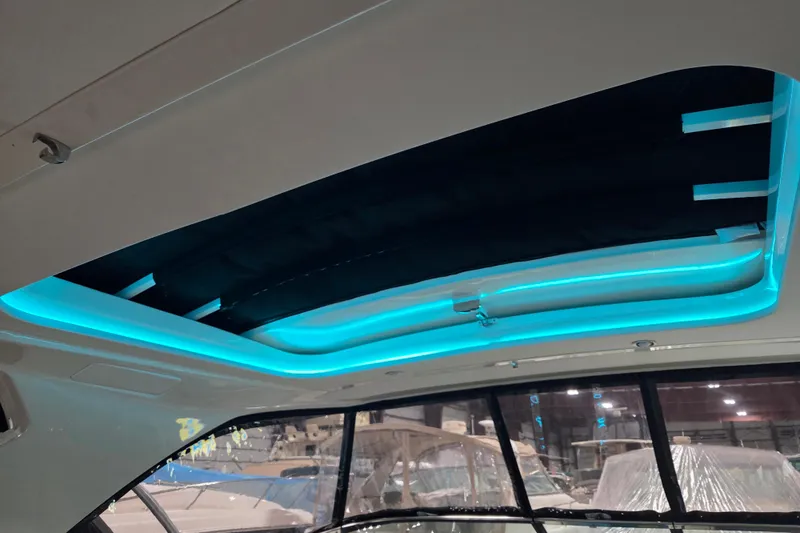 Slide: The Image of 2023 Sea Ray SLX 350 boat under warehouse roof with blue LED lighting. - 51