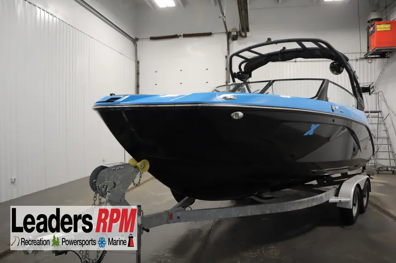 The Image of 2023 Yamaha Boats 222XD in showroom, black and blue design, on trailer. - 1