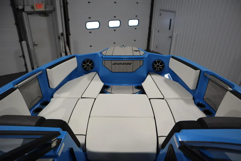 Slide: The Image of 2023 Yamaha Boats 222XD interior with blue and white seating in a garage setting. - 11