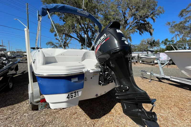 Slide: The Image of 2015 NauticStar 203SC Sport Deck boat with Suzuki outboard motor, parked outdoors. - 3