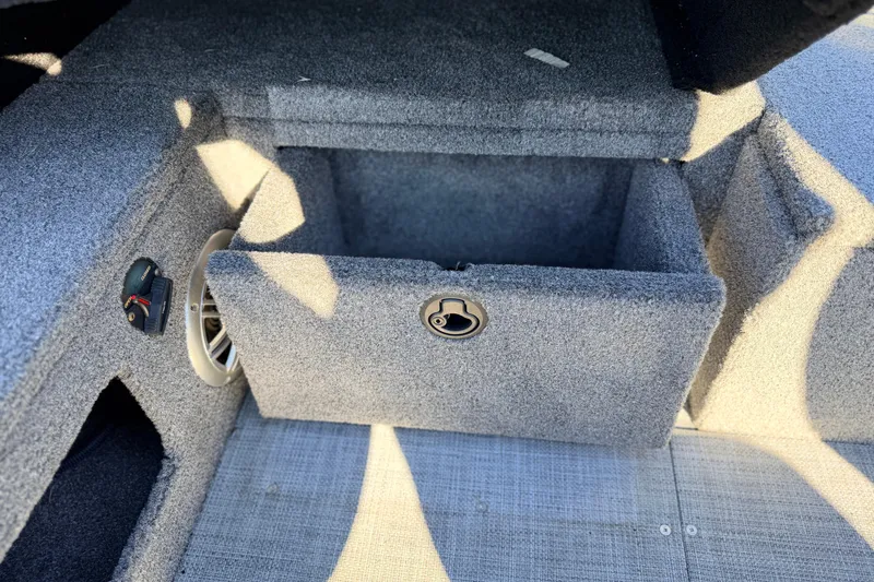 Slide: The Image of 2024 Alumacraft Competitor 175X Sport storage compartment with speaker and carpeted interior. - 20