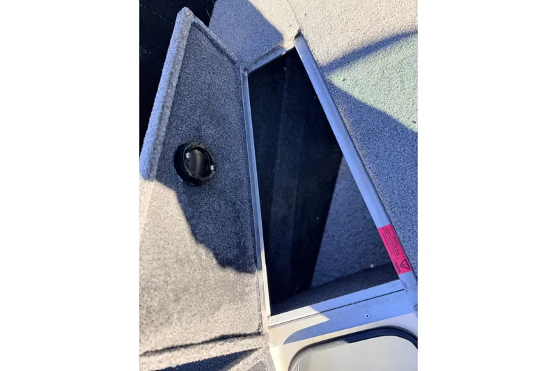 Slide: The Image of 2024 Alumacraft Competitor 175X Sport boat storage compartment, open and carpeted. - 28