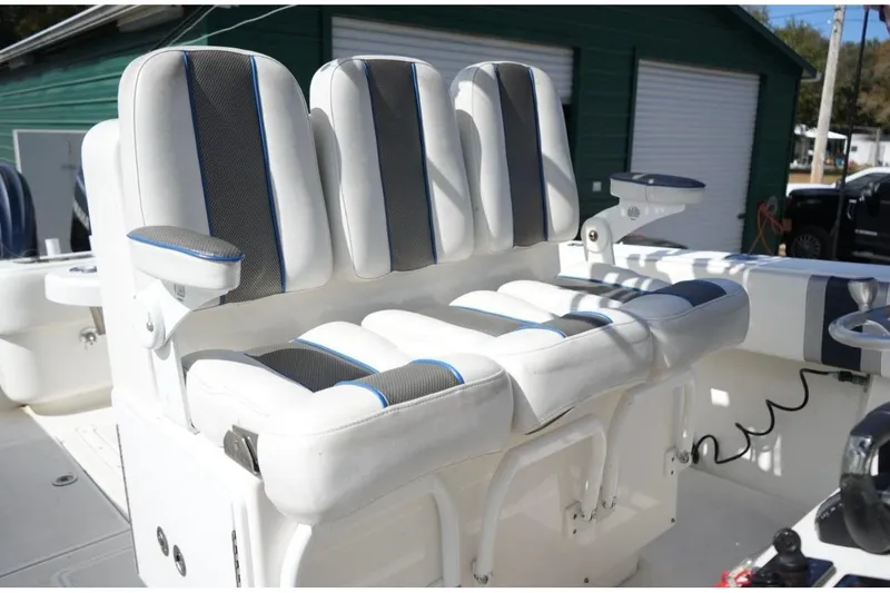 Slide: The Image of Contender 36 Open 2000 boat with cushioned seating and armrests, docked near a green building. - 11