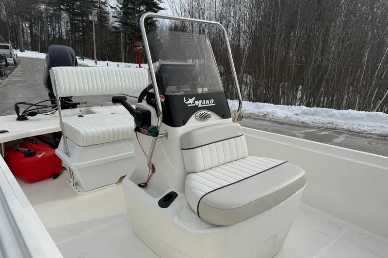 Slide: The Image of 2016 Mako Pro Skiff 17 CC boat with white seating and console, parked near snowy trees. - 25