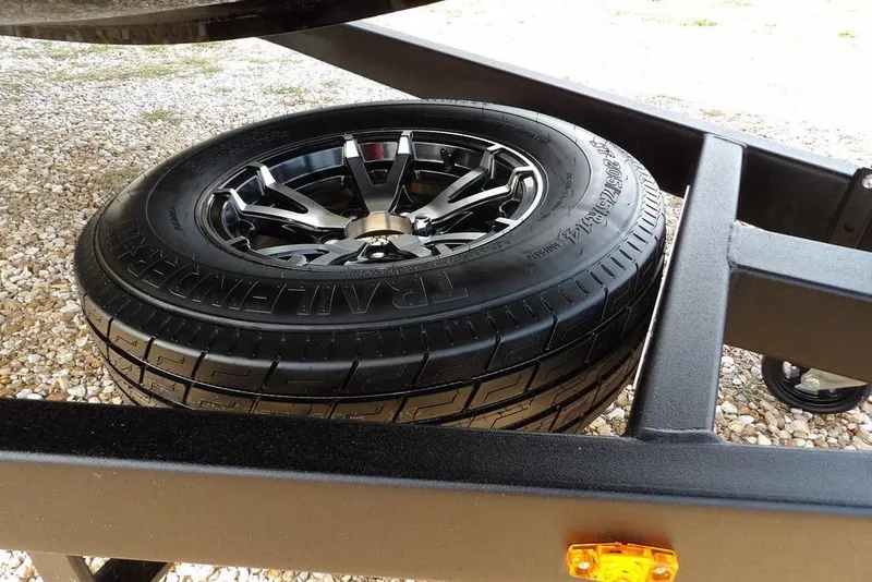 Slide: The Image of 2026 Crestliner XF 189 trailer tire with alloy wheel on gravel surface. - 35