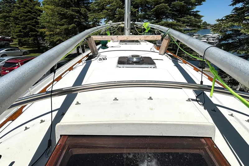 Slide: The Image of 1985 Nonsuch 30 Ultra sailboat deck with rigging, surrounded by trees and parked cars. - 23