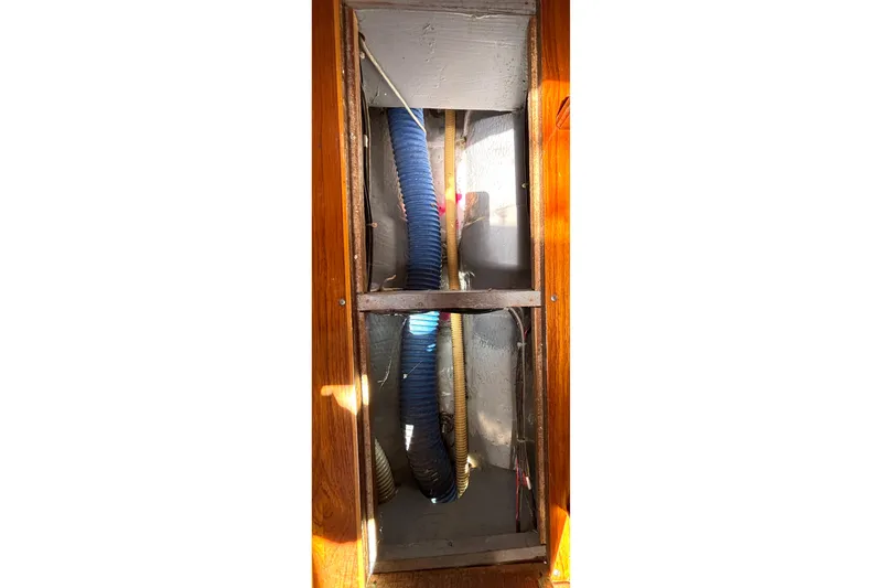 Slide: The Image of Interior view of a 1985 Nonsuch 30 Ultra sailboat showing exposed wiring and hoses. - 47