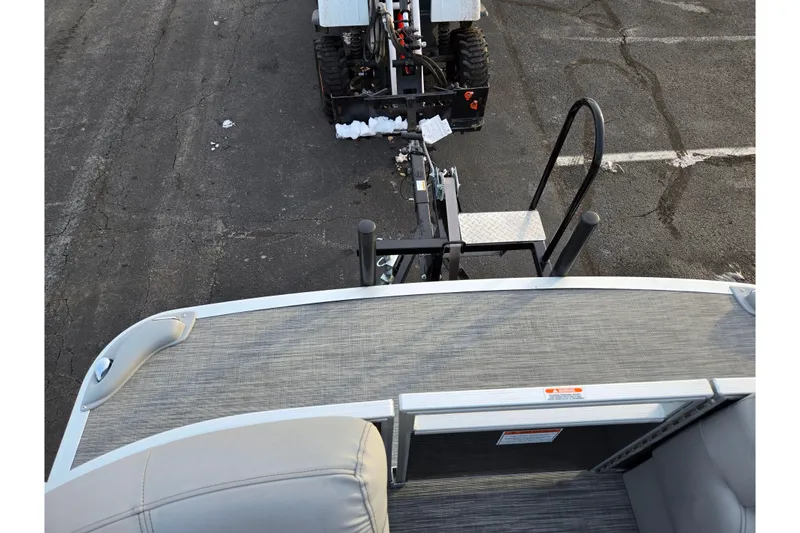 Slide: The Image of 2021 Bennington L 22 Quad Bench pontoon boat with dock ladder and tractor in background. - 24