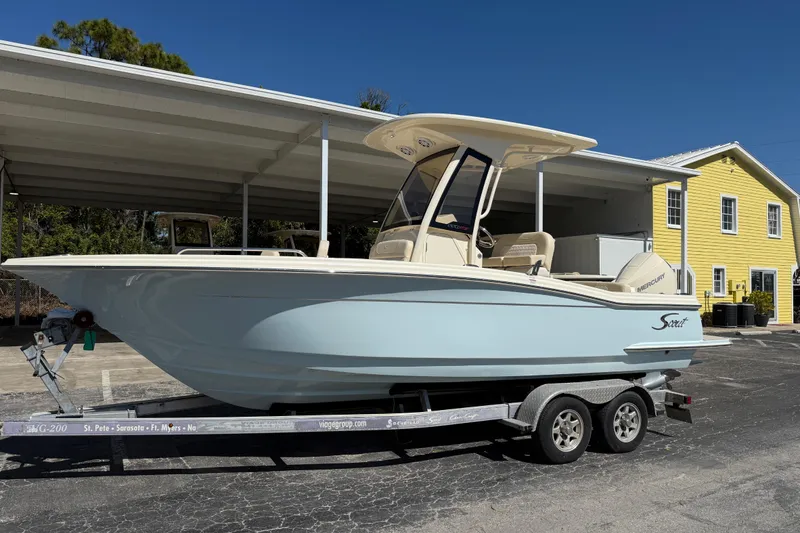 The Image of 2026 Scout 220 XSF boat on trailer, parked near a yellow building. - 0