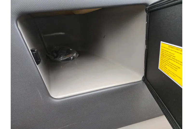 Slide: The Image of 2021 Moomba Max glove compartment interior with storage space and safety label. - 17