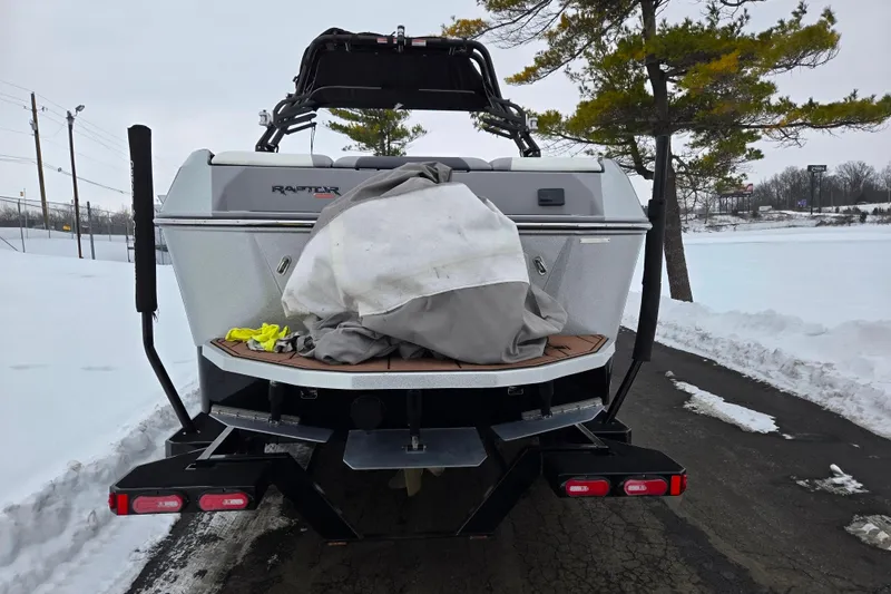 Slide: The Image of 2021 Moomba Max boat rear view on snowy road, covered with tarp. - 2