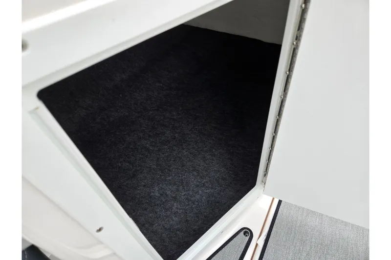 Slide: The Image of Open storage compartment in 2023 Yamaha AR195 boat, featuring a carpeted interior. - 15