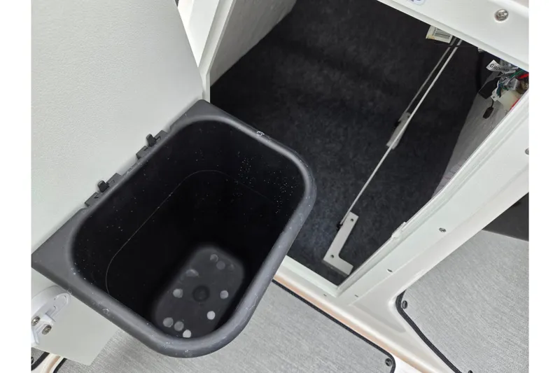 Slide: The Image of 2023 Yamaha AR195 boat storage compartment with black bin and open door. - 16
