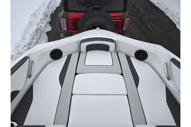 Slide: The Image of 2023 Yamaha AR195 boat interior with cushioned seating, parked near a red vehicle in snowy surroundings. - 17