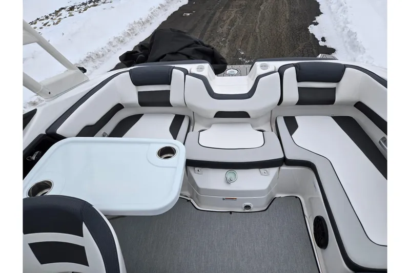 Slide: The Image of 2023 Yamaha Boats AR195 interior with white and black seating, table, and snowy background. - 21