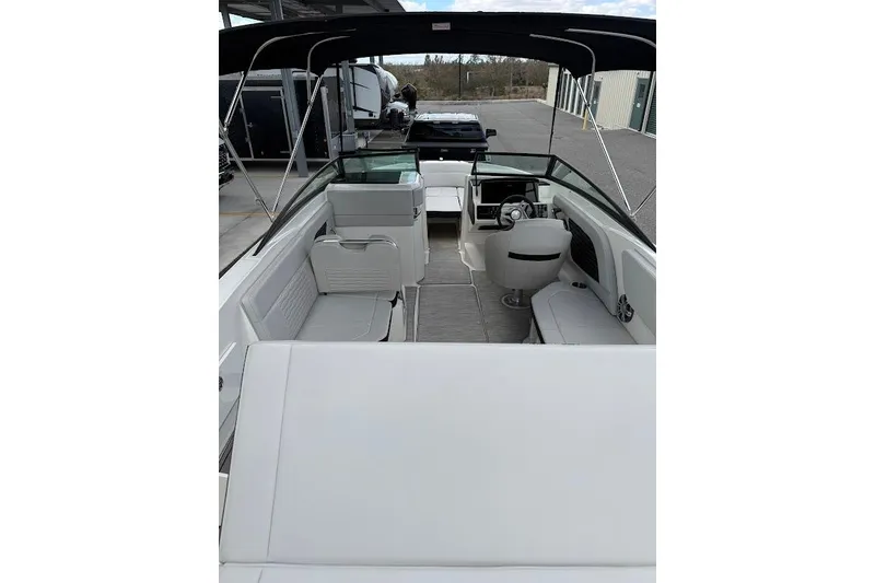 Slide: The Image of 2023 Sea Ray SPX 230 boat interior with seating and steering wheel, docked outdoors. - 9