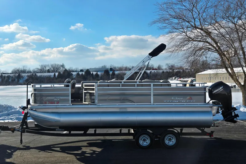 The Image of 2024 Sun Tracker Fishin' Barge 20 DLX pontoon boat on trailer, winter landscape. - 0