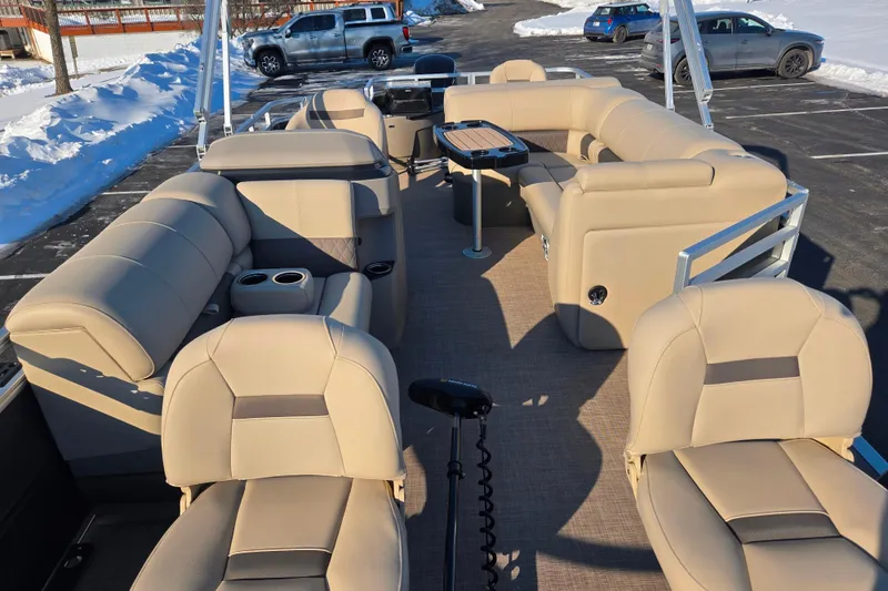 Slide: The Image of 2024 Sun Tracker Fishin' Barge 20 DLX interior with beige seating and table, parked in snowy lot. - 11