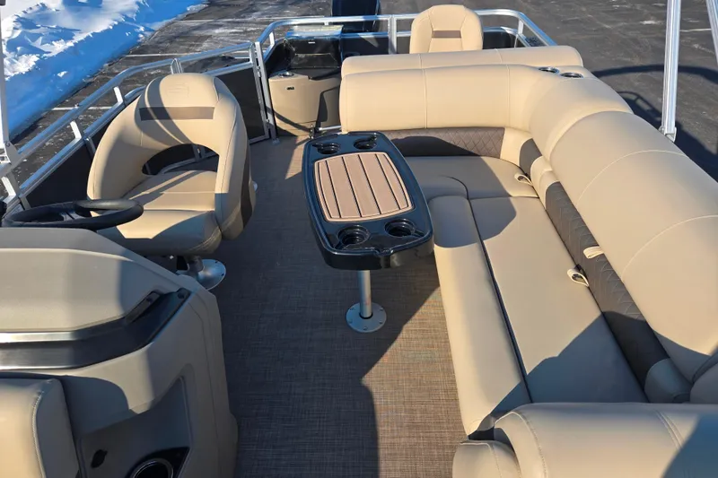 Slide: The Image of 2024 Sun Tracker Fishin' Barge 20 DLX interior with beige seating and table. - 12