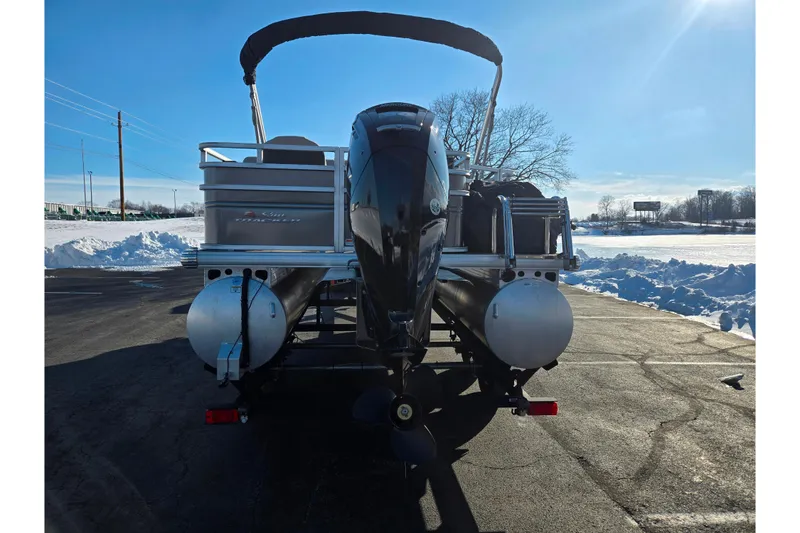 Slide: The Image of 2024 Sun Tracker Fishin' Barge 20 DLX pontoon boat, rear view, parked on snowy pavement. - 2