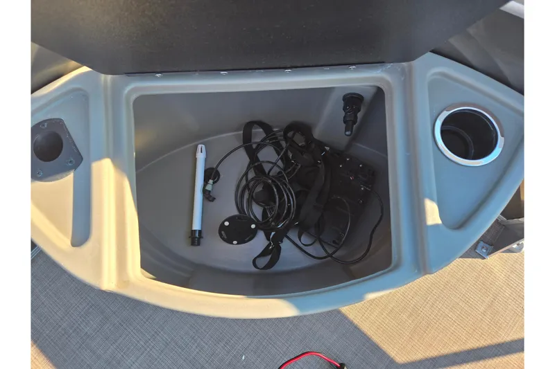 Slide: The Image of 2024 Sun Tracker Fishin' Barge 20 DLX storage compartment with cables and cup holder. - 24