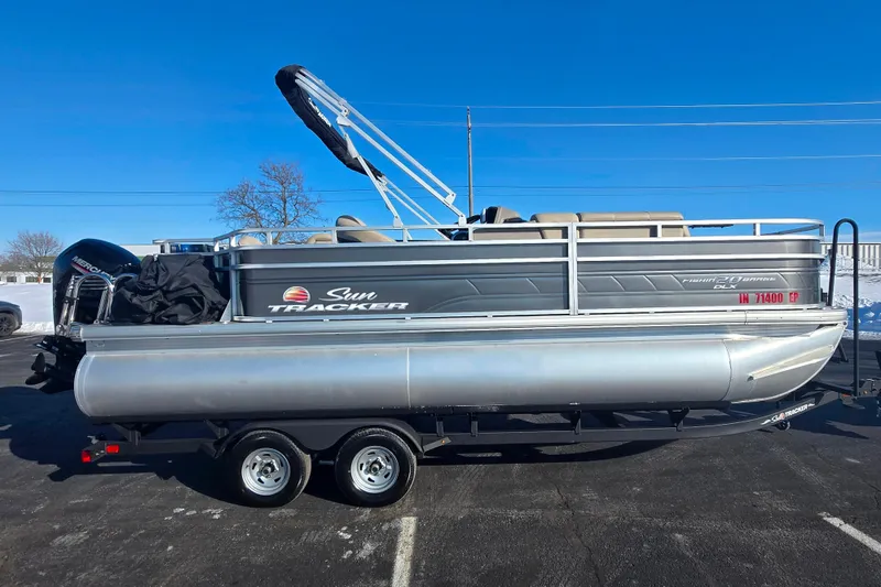 Slide: The Image of 2024 Sun Tracker Fishin' Barge 20 DLX pontoon boat on trailer, parked outdoors. - 4