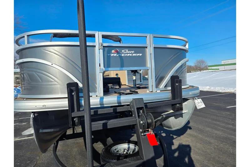 Slide: The Image of 2024 Sun Tracker Fishin' Barge 20 DLX pontoon boat on trailer, parked on asphalt. - 6