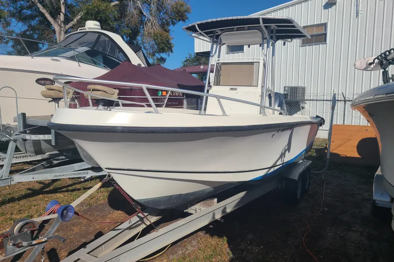 The Image of 1995 Mako 201 Center Console boat on trailer, parked outdoors near other boats. - 0