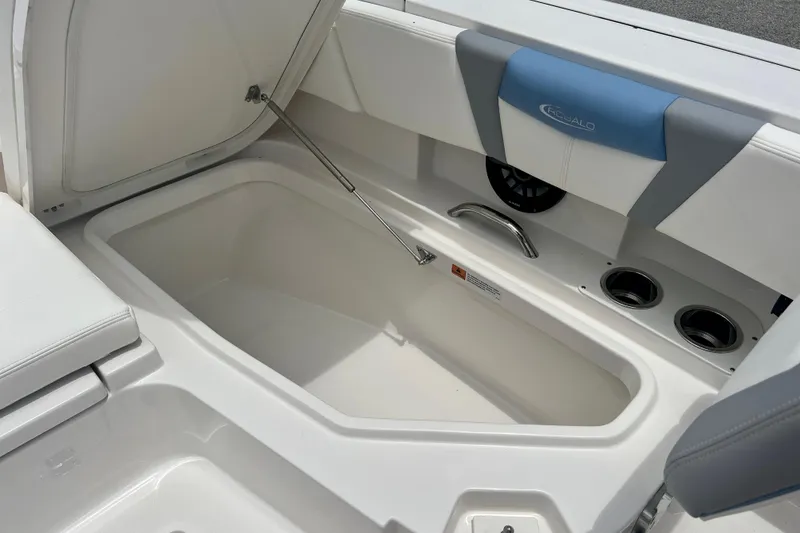 Slide: The Image of 2025 Robalo 266 Cayman SD boat storage compartment with cushioned seating and cup holders. - 19