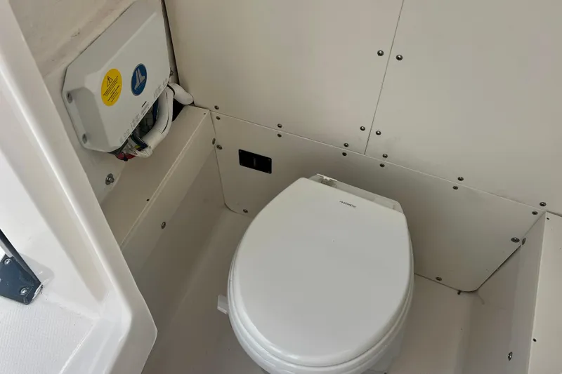 Slide: The Image of 2025 Robalo 266 Cayman SD boat interior with compact marine toilet. - 24