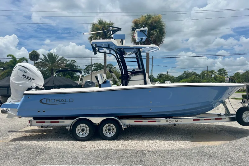 Slide: The Image of 2025 Robalo 266 Cayman SD boat on trailer, blue hull, Yamaha engine, outdoor setting. - 7