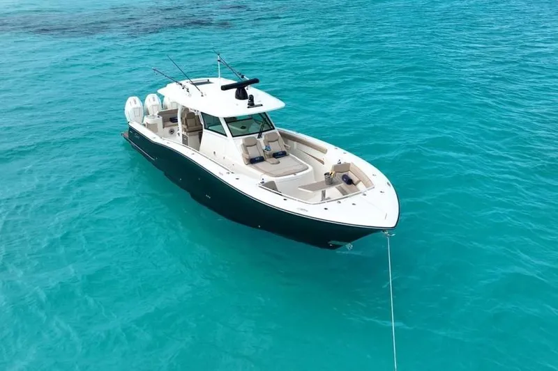 Slide: The Image of 2024 Scout 400 LXF boat anchored in clear turquoise water. - 12