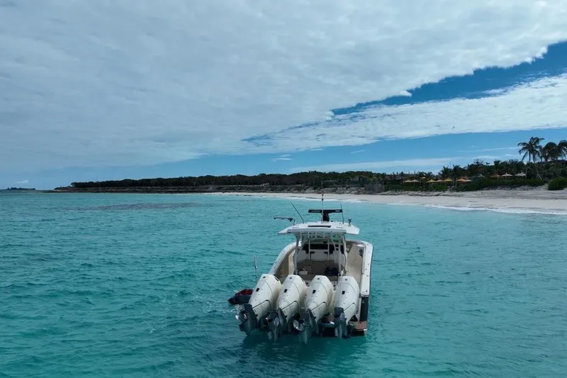 Slide: The Image of 2024 Scout 400 LXF boat anchored in turquoise waters near a sandy beach. - 14