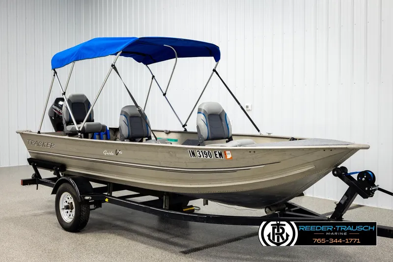 Slide: The Image of 1999 Tracker Pro Deep V-16 boat with blue canopy on trailer, displayed indoors. - 3