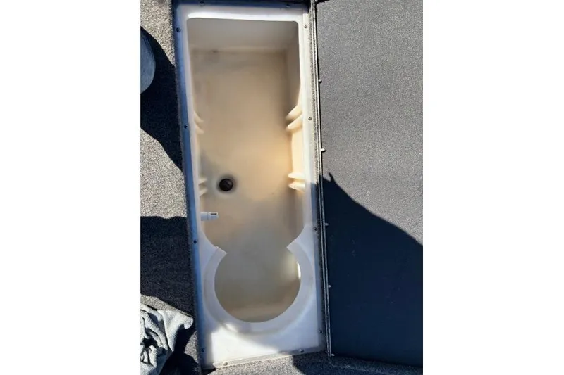 Slide: The Image of 2023 Crestliner XFC 189 boat storage compartment, open and empty, with a drain plug. - 17