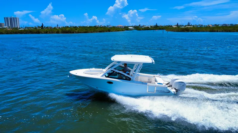 Slide: The Image of 2025 Robalo R257 Dual Console boat cruising on blue water under clear sky. - 10