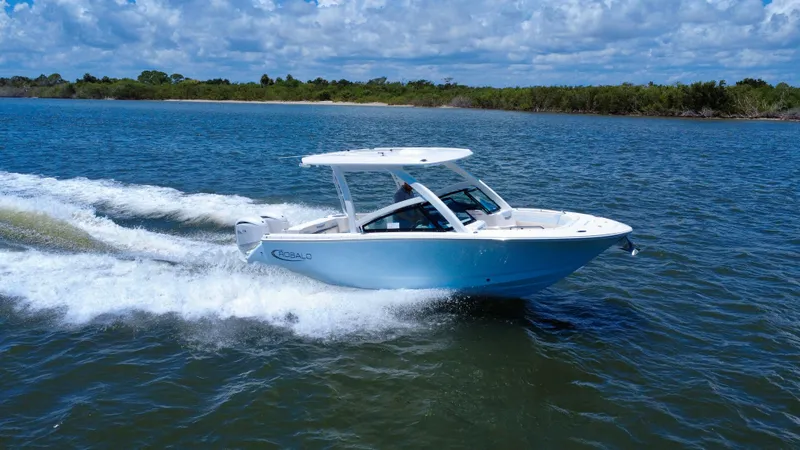 Slide: The Image of 2025 Robalo R257 Dual Console boat cruising on open water under a blue sky. - 13