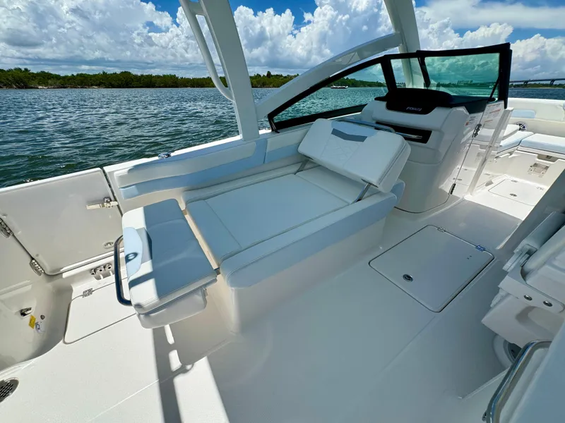 Slide: The Image of 2025 Robalo R257 Dual Console boat interior with seating, open water view, and clear skies. - 22