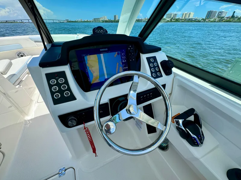 Slide: The Image of 2025 Robalo R257 Dual Console helm with navigation display, steering wheel, and throttle controls. - 36