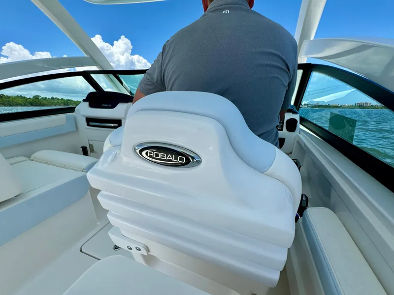 Slide: The Image of 2025 Robalo R257 Dual Console boat interior with driver, featuring sleek white seating. - 46