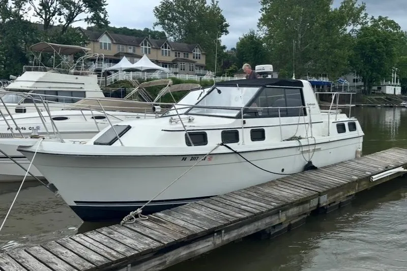 The Image of 1985 Carver 28 Riviera docked at a marina with scenic background. - 1