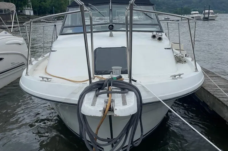 Slide: The Image of 1985 Carver 28 Riviera boat docked, front view with ropes and water background. - 4