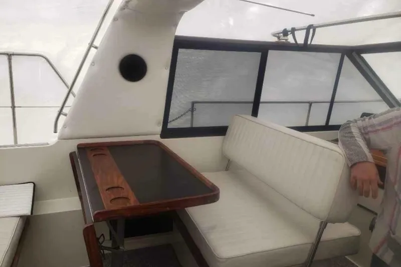 Slide: The Image of 1985 Carver 28 Riviera interior with white seating and wooden table. - 7