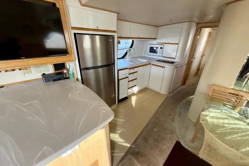 Slide: The Image of Luxurious 1999 Bluewater 5800 yacht interior with modern kitchen and dining area. - 21