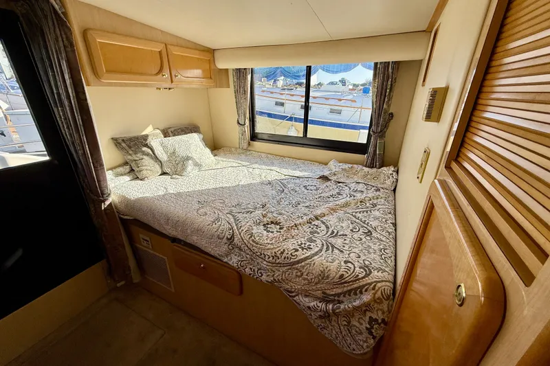 Slide: The Image of Cozy bedroom interior of 1999 Bluewater 5800 yacht with patterned bedding and window view. - 28