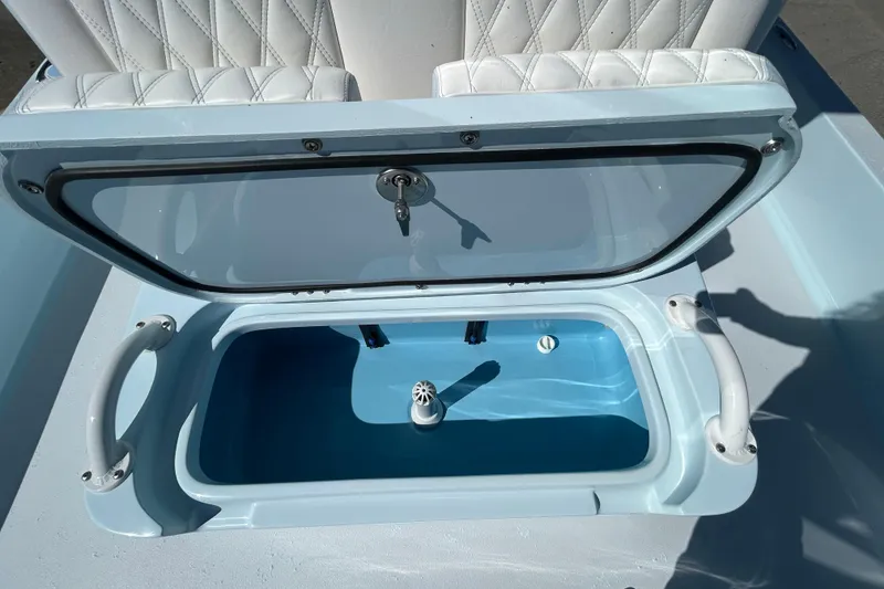 Slide: The Image of Livewell compartment on 2026 Shallow Sport 25 X3 boat with open lid and white seating. - 11