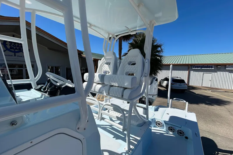 Slide: The Image of 2026 Shallow Sport 25 X3 boat with elevated seating and steering console in a marina setting. - 12