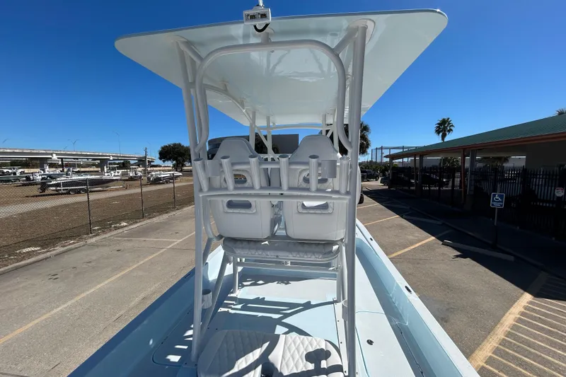 Slide: The Image of 2026 Shallow Sport 25 X3 boat with elevated seating and canopy in a parking area. - 17